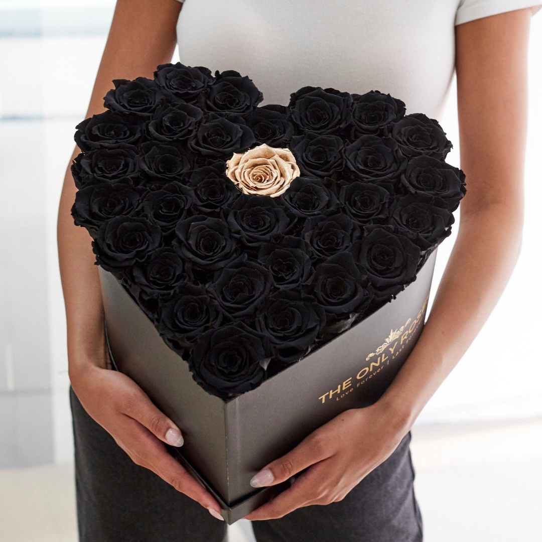 Girl is holding a heart shaped rose hat box with all black roses